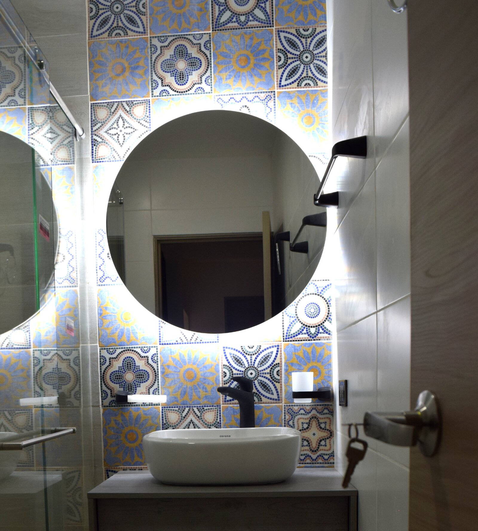 Baño con enchape en mosaico y espejo circular retroiluminado